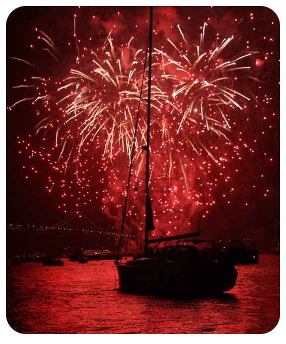Sailboat with red fireworks exploding in the background