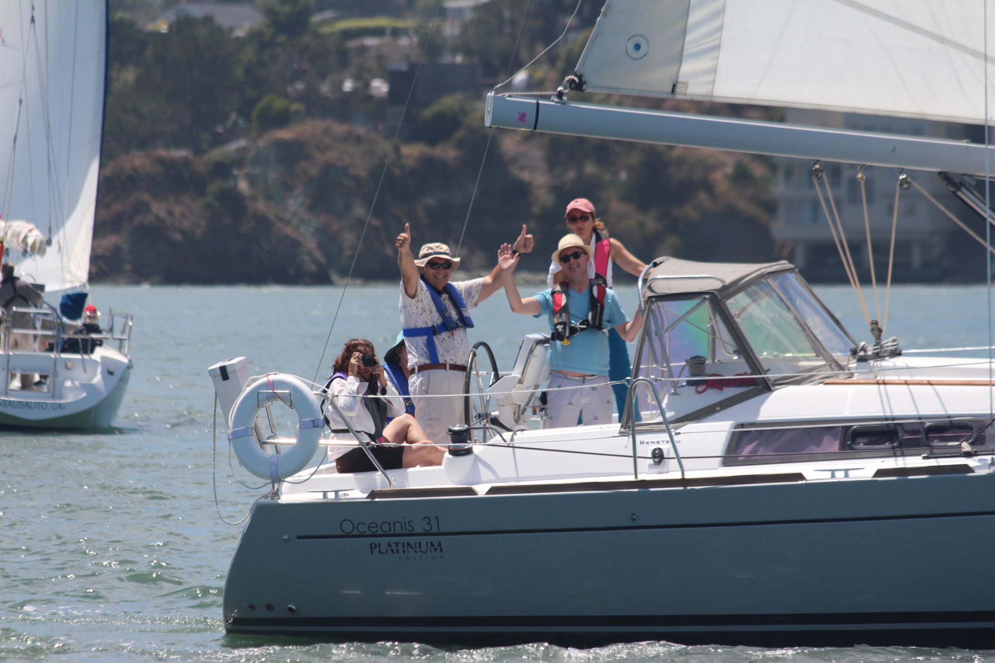People waving from the cockpit of a sailboat
