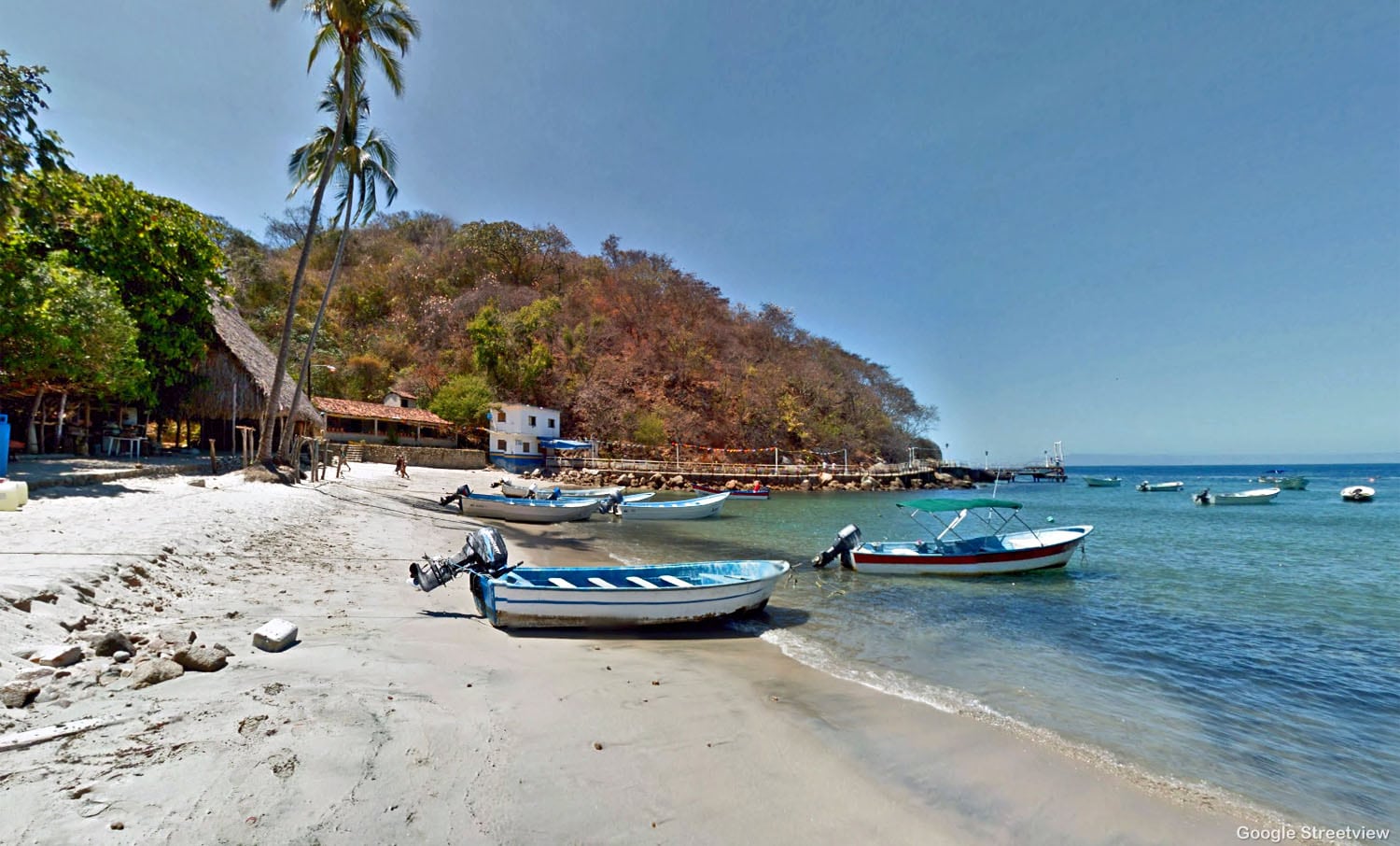 Couple of small blue fishing boats on an empty tropical beach